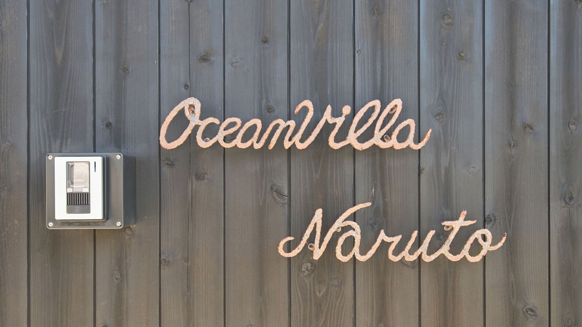 A wooden wall with the words "Oceanvilla Naruto" written in cursive.