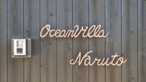 A wooden wall with the words "Oceanvilla Naruto" written in cursive. - Ocean Villa Naruto (Naruto)