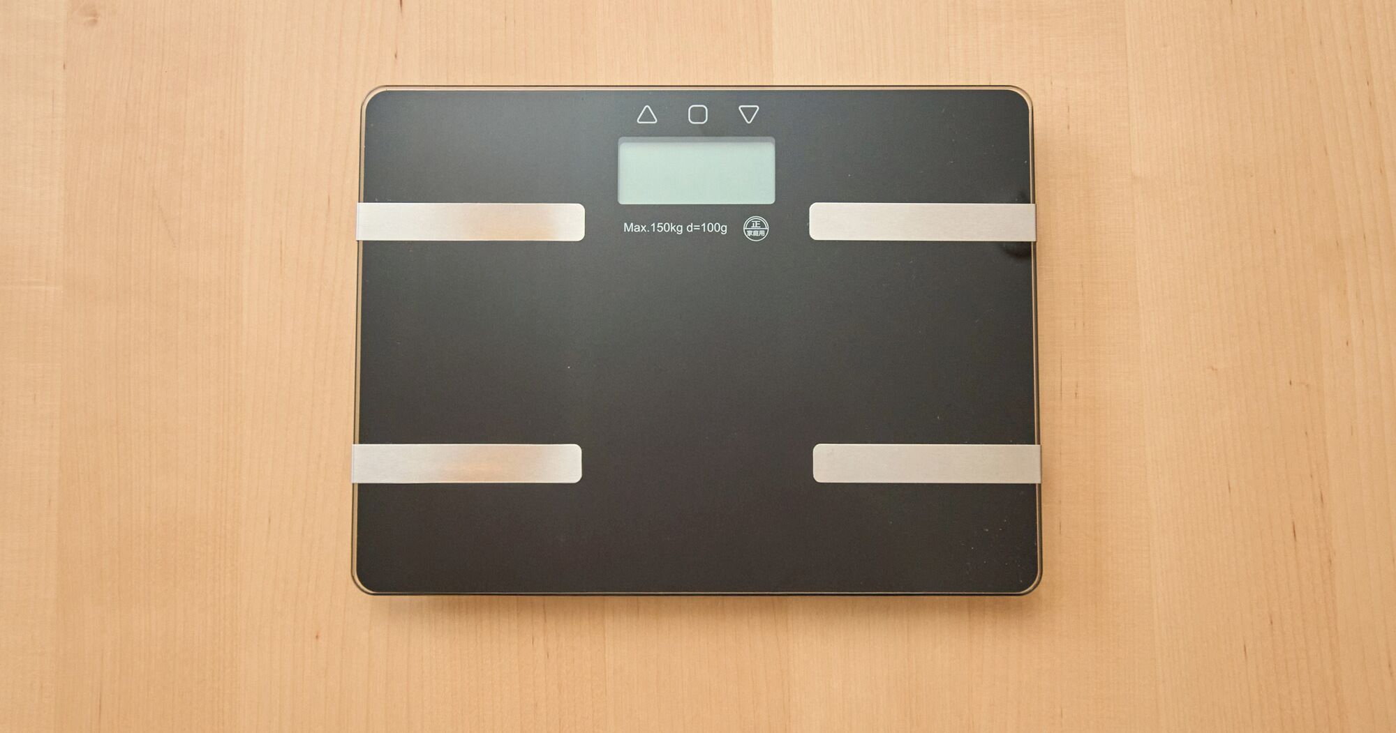 A digital bathroom scale with a maximum capacity of 150kg, placed on a wooden floor.