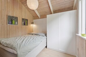 Camera da letto con un letto, un armadio, pareti in legno e due quadri appesi.