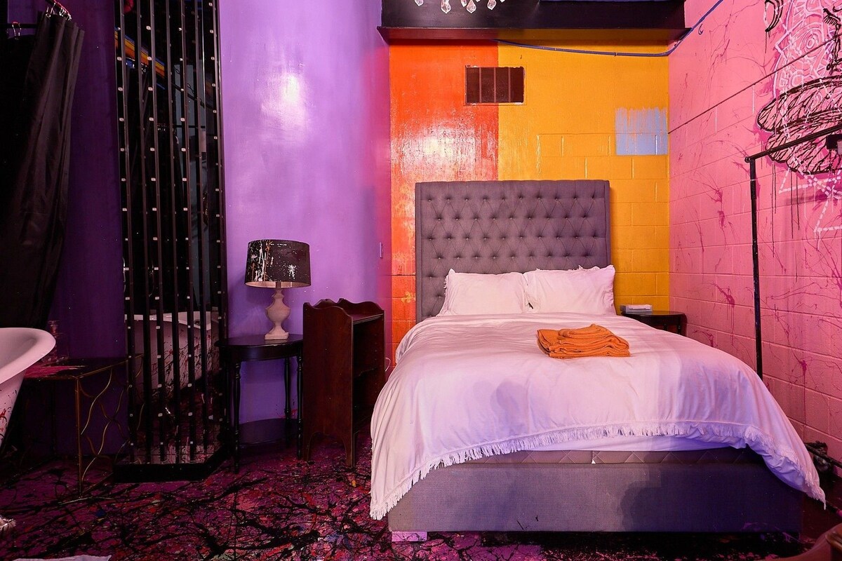 A bedroom with a bed, a nightstand, a lamp, and a chair.