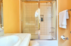 A bathroom with a glass-enclosed shower, a bathtub, and a toilet. - Beverly Hills Spanish (Beverly Hills)