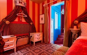 A bedroom with a striped wall, a canopy bed, a small bedside table, a dresser, and a patterned rug. - Beverly Hills Spanish (Beverly Hills)