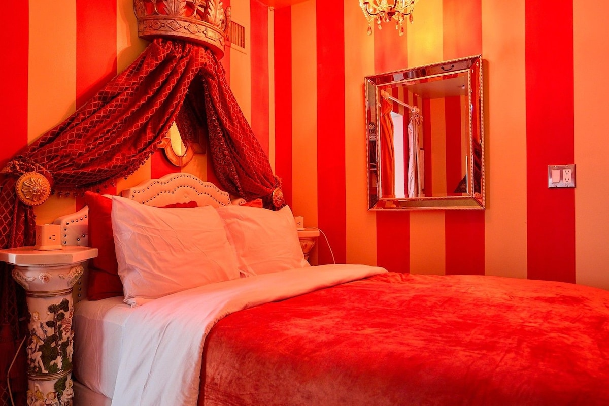 A bed with a canopy, a bedside table, and a mirror on the wall.