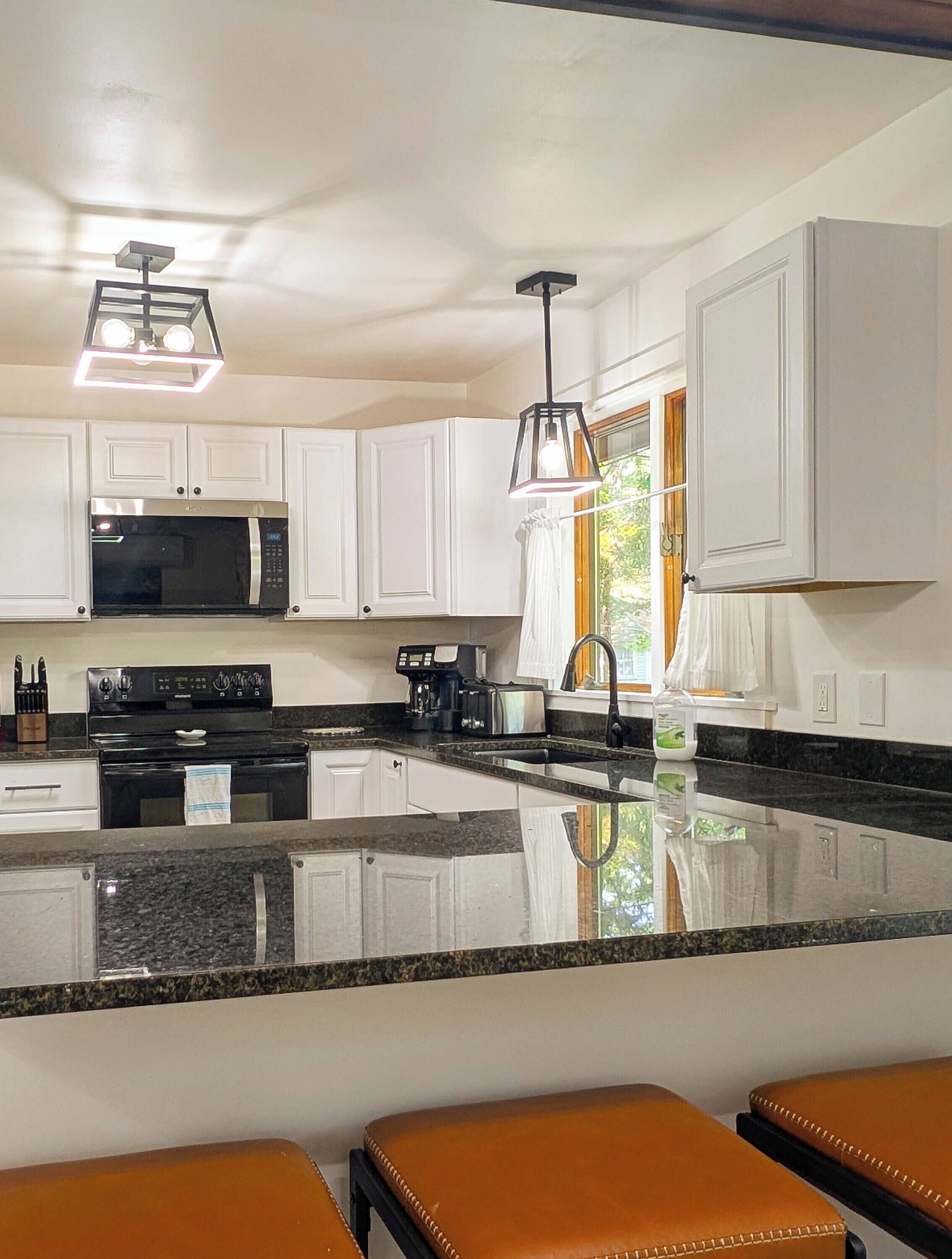 A modern kitchen with white cabinets, a black stove, and a granite countertop.