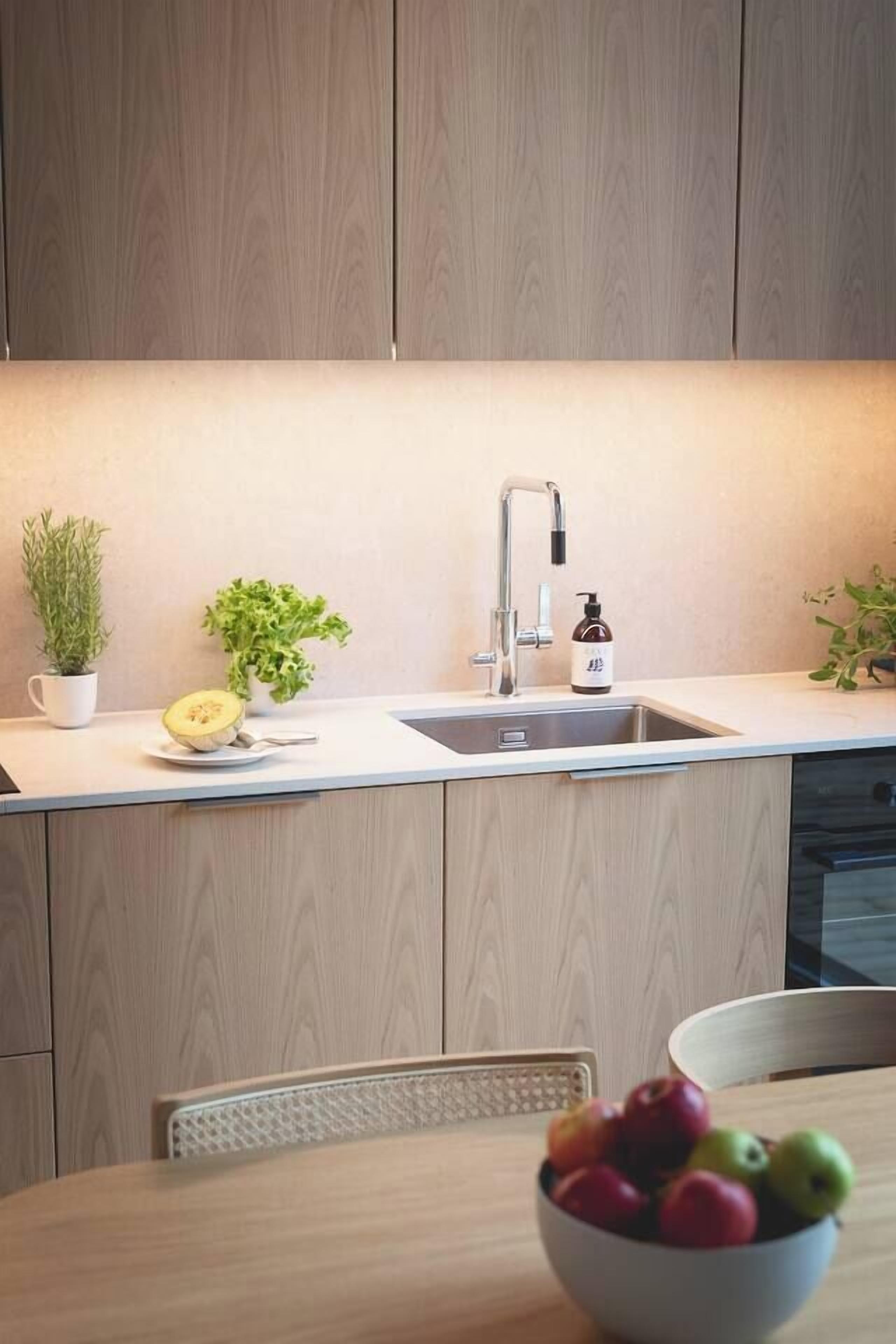 A modern kitchen with a wooden countertop, a sink, and a bowl of fruit on the table.