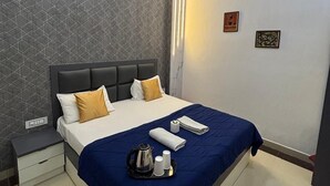 Una habitación de hotel moderna con una cama grande, una mesita de noche, un ventilador de techo y una pared con un diseño geométrico.