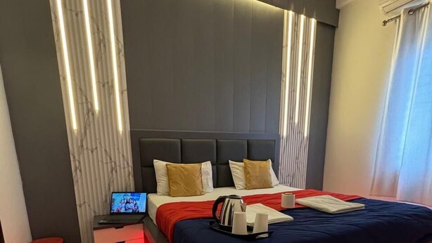 Un dormitorio moderno con una cama grande, una mesita de noche con una computadora portátil y un suelo iluminado con luz roja.