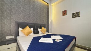 Una habitación de hotel con una cama, una mesita de noche, un muro con un diseño geométrico y dos cuadros enmarcados.