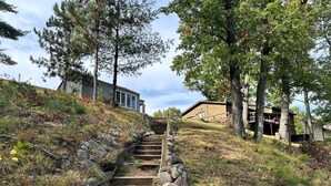 A wooden staircase leading up a grassy hill with a house at the top. - Rustic Lake Nokomis Cabin with Hot Tub, Trails, and Family Fun for 10! (Tomahawk)