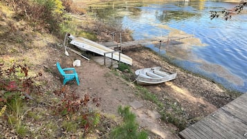 Une zone au bord du lac, avec un quai, un petit bateau et une chaise bleue.