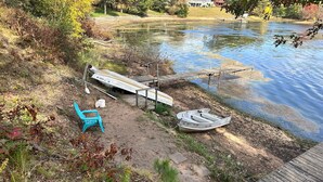 A lakeside dock with a boat and a chair.