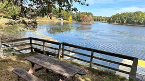 A wooden picnic table and bench by a lake with a wooden railing.