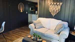 A modern living room with a light-colored sofa, a coffee table with plants, and decorative wall hangings.