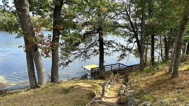 A wooden staircase leading down to a dock by a lake, surrounded by trees.