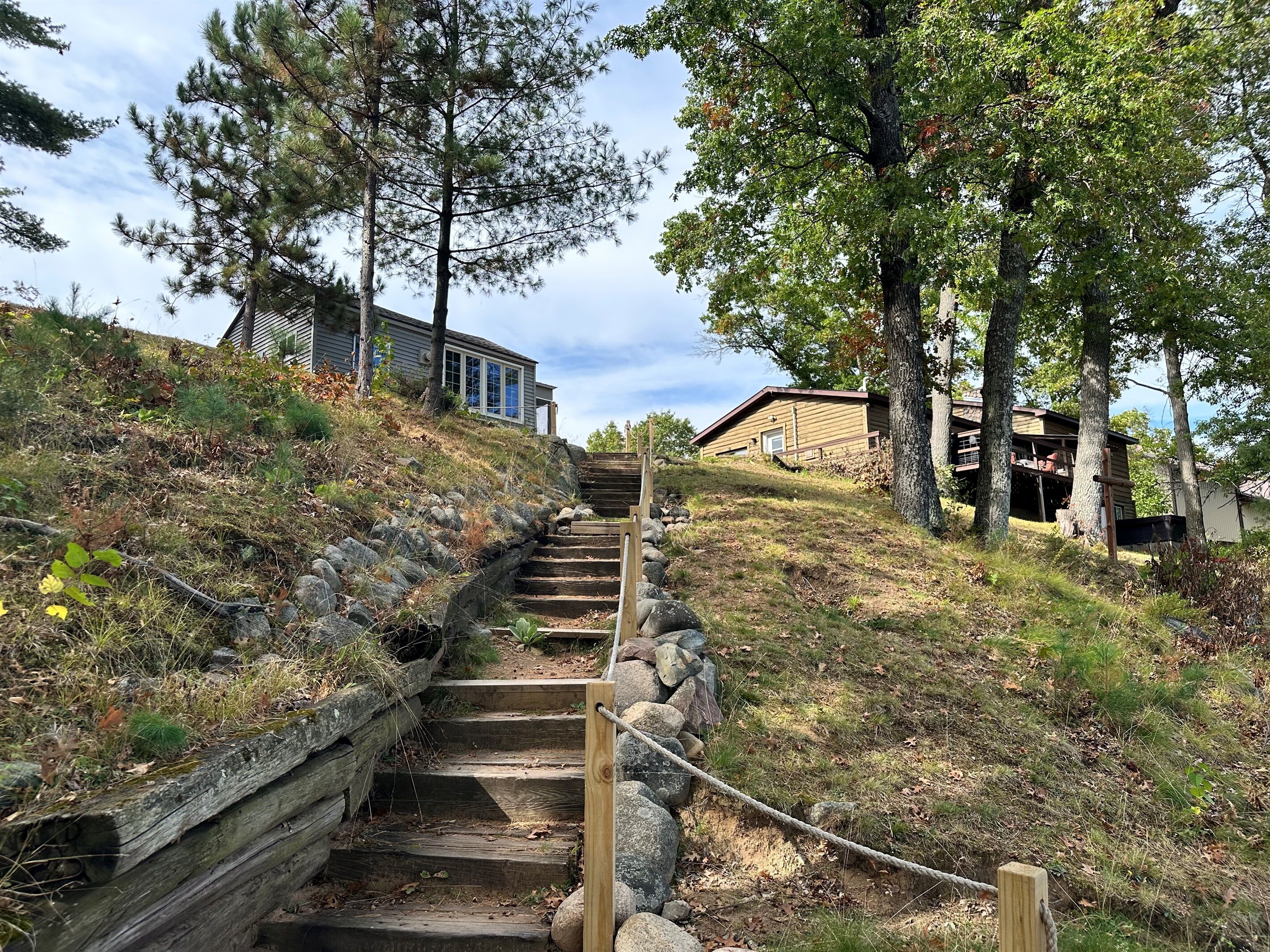 A wooden staircase leading up a grassy slope with a house at the top.