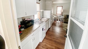 A compact kitchen with white cabinets, a gas stove, and a refrigerator. - Rustic Lake Nokomis 2BD/1Bath Lakeside Cabin - Cabin #3 (Tomahawk)