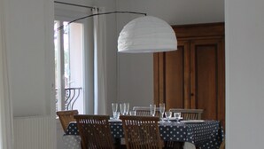 Een eetgedeelte met een tafel gedekt voor vier personen, houten stoelen en een witte hanglamp.