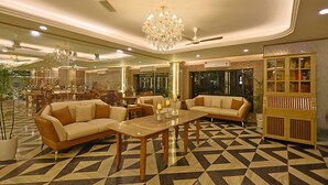 A spacious lobby with a geometric patterned floor, two sofas, a coffee table, a chandelier, and a bookshelf. - FlxHo Horizon ONE - Luxury Hotel & Residences Golf Course Road, 2 Min from 42-43 Metro Station (Gurugram)