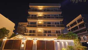 A multi-story hotel with balconies and a well-lit entrance. - FlxHo Horizon ONE - Luxury Hotel & Residences Golf Course Road, 2 Min from 42-43 Metro Station (Gurugram)