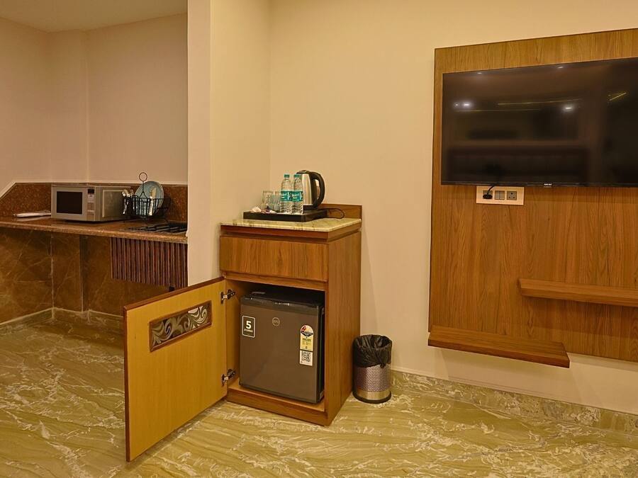 Una kitchenette compacta equipada con microondas, refrigerador y un lavamanos pequeño.