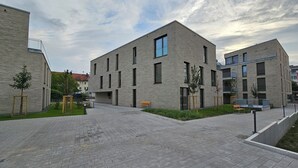 A modern building with a flat roof, rectangular windows, and a brick facade.