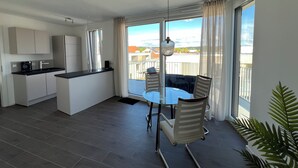 A modern apartment with a kitchen, dining area, and balcony.