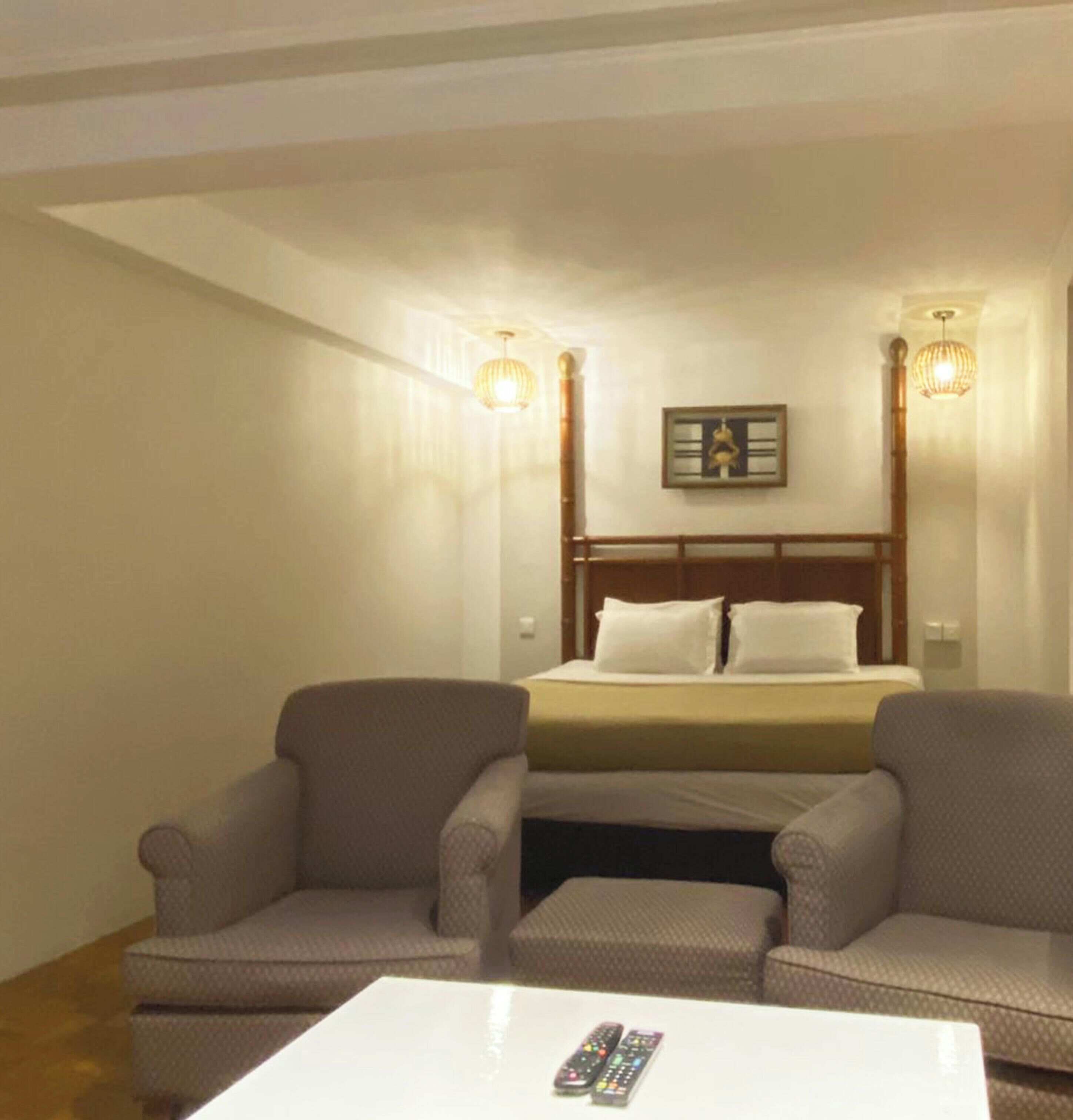 A hotel room with a bed, two armchairs, a small table, and a door.