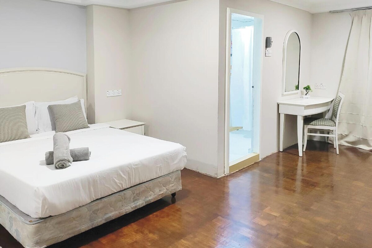 Un dormitorio con cama, mesita de noche y un pequeño escritorio con silla.
