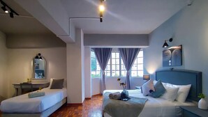 Habitación de hotel con dos camas, un escritorio, un espejo y vista al exterior.