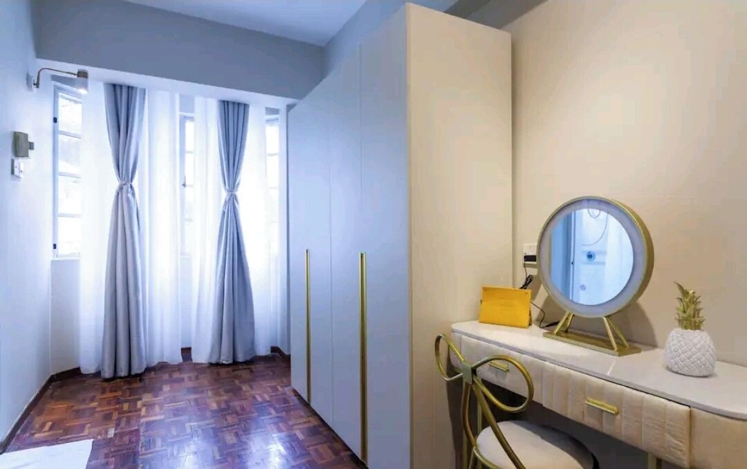 A room with a wooden floor, a vanity with a mirror, a small yellow box, and a pineapple decoration.