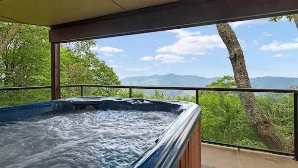 Un jacuzzi con vista a montañas y árboles.