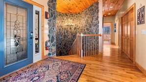 Una escalera de madera con un muro de piedra, un tapete estampado y una puerta azul con un panel de vidrio.