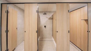 A modern restroom with wooden lockers, a tiled floor, and a shower area. - Bounce Airlie Beach (Airlie Beach)