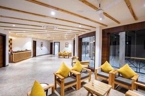 A spacious lobby with wooden furniture and a reception desk. - Shervani Pebbles And Pine, Corbett (Ramnagar)