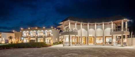A multi-story hotel with a central courtyard, balconies, and a well-lit facade.