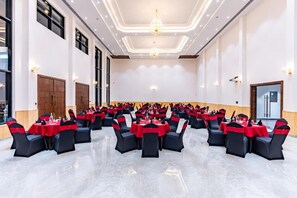 A large banquet hall with rows of tables and chairs, a chandelier, and a polished floor. - Shervani Pebbles And Pine, Corbett (Ramnagar)