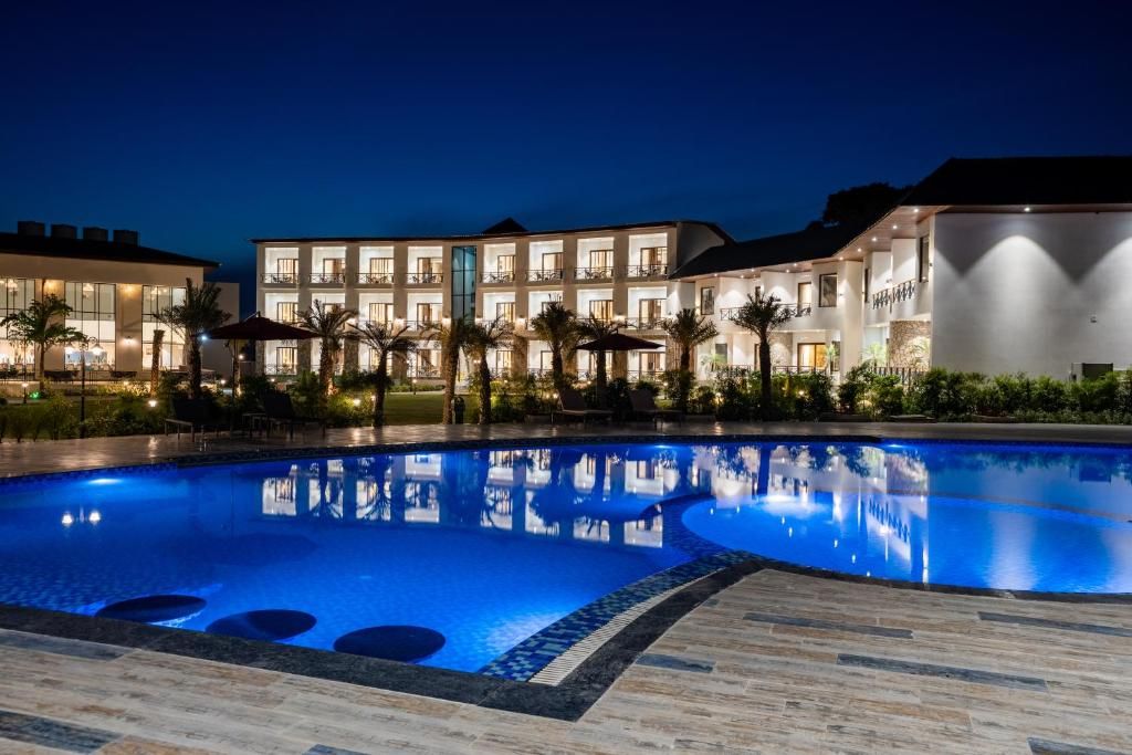 Une piscine dans laquelle se reflètent les bâtiments de l’hôtel la nuit.