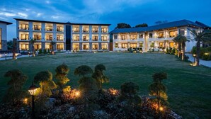 A multi-story hotel with a well-lit courtyard and landscaped garden. - Shervani Pebbles And Pine, Corbett (Ramnagar)