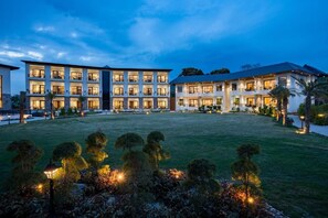 A multi-story hotel with a well-lit courtyard and landscaped garden. - Shervani Pebbles And Pine, Corbett (Ramnagar)