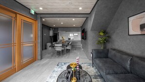 Un intérieur moderne avec un canapé, une table basse ornée de bougies, un coin repas et une cuisine en arrière-plan.