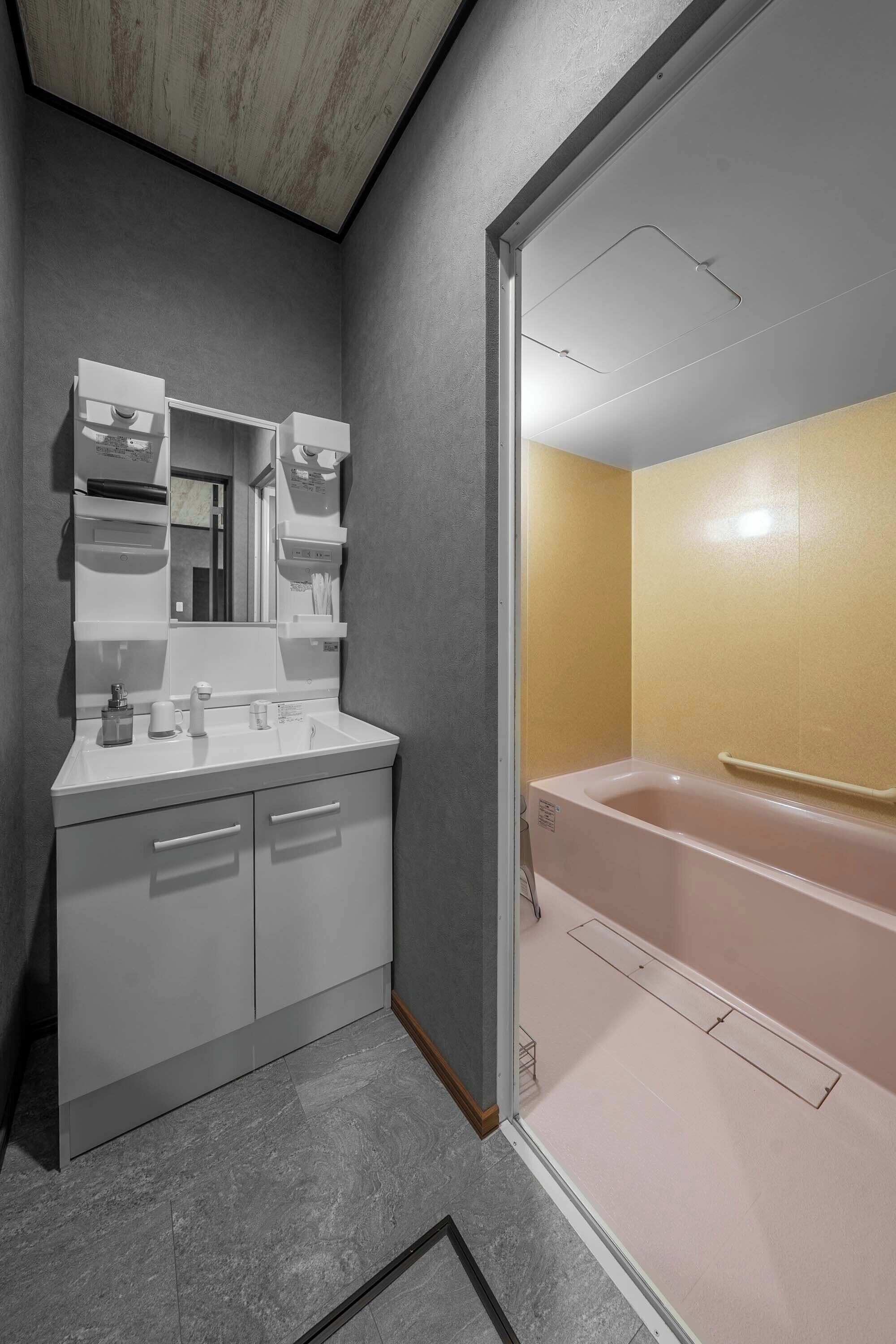 A bathroom with a white vanity, a mirror, a sink, and a bathtub.