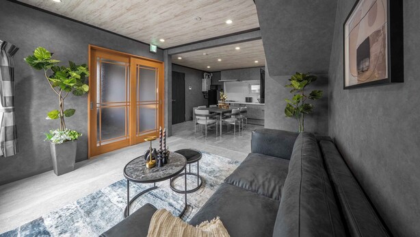 Un salon moderne avec un canapé gris, une table basse ronde et, au fond, un coin repas.