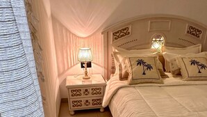 Ein Schlafzimmer mit einem Bett, Nachttischen, einer Lampe und Teppichen mit Muster.