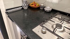 Eine Küche mit schwarzer Granitabdeckung, einem Gasherd und dekorativen Vasen.