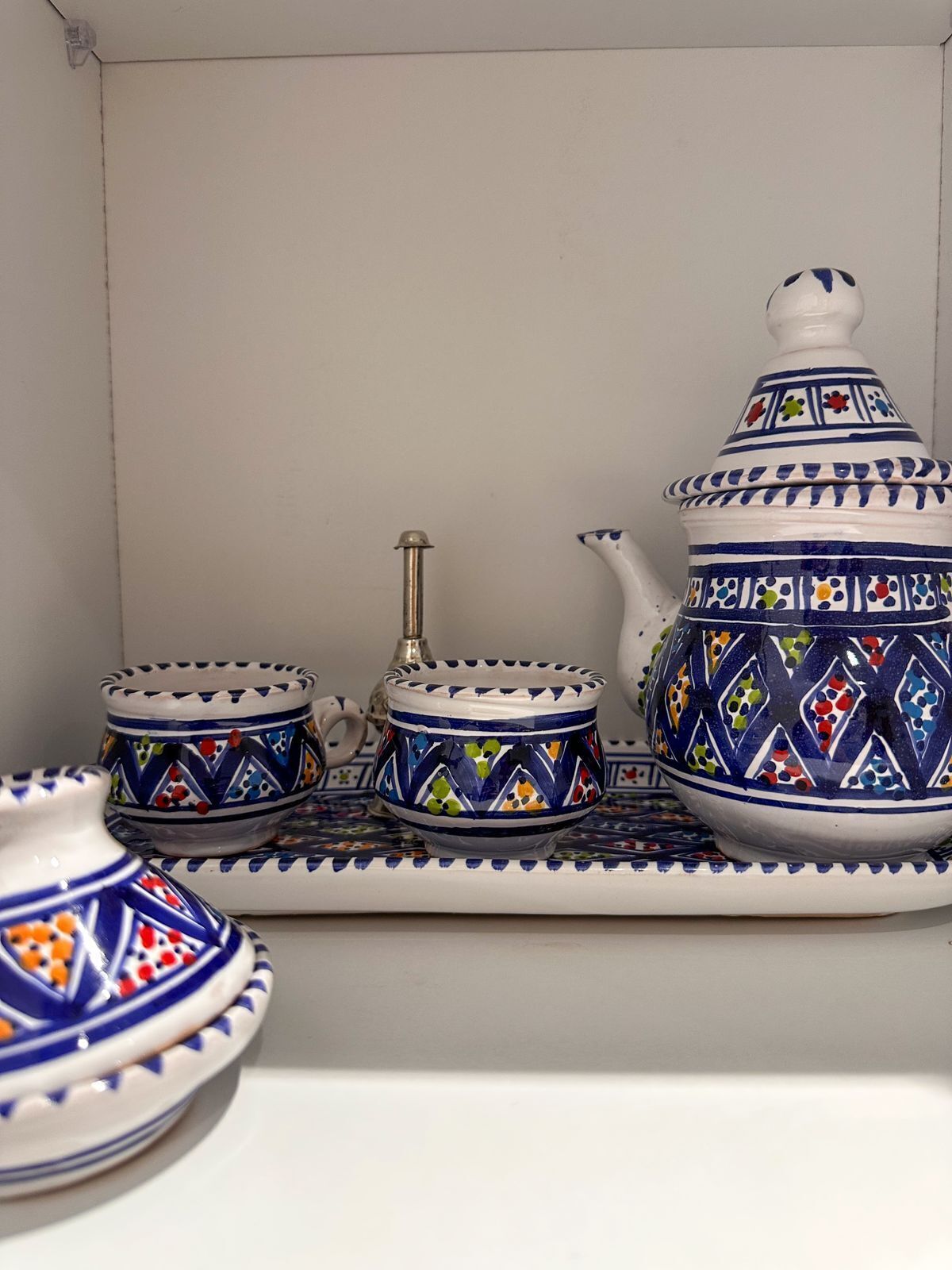 Een set witte keramieken theepotten met blauwe en kleurrijke patronen, een bijpassende theepot, en een dienblad.