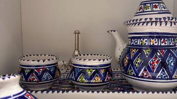 Een set witte keramieken theepotten met blauwe en kleurrijke patronen, een bijpassende theepot, en een dienblad.