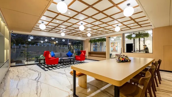 A modern interior with a dining area, seating, and a view through large windows. - Hotel Bawa Gurgaon, Medanta (Gurugram)