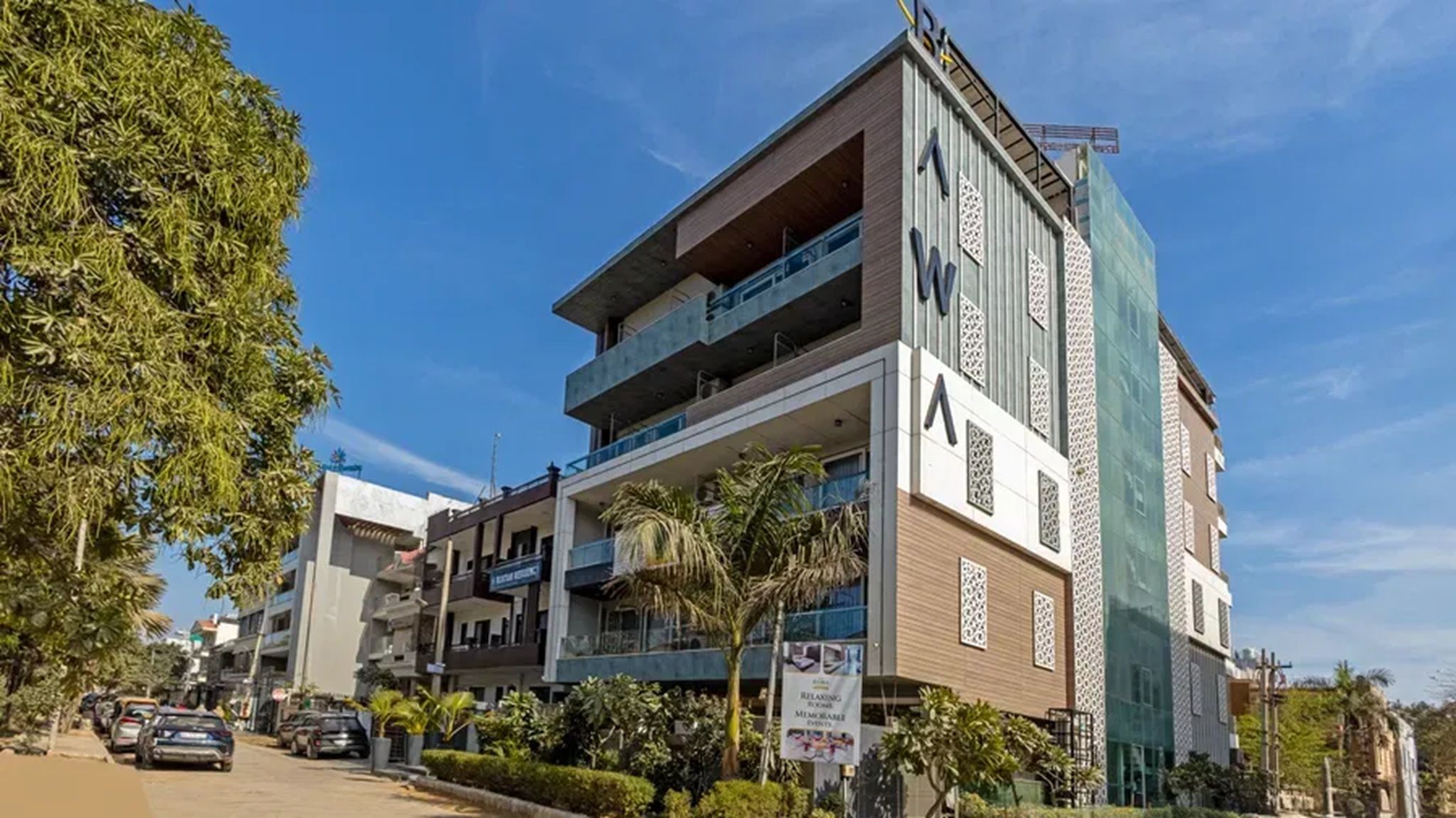 A multi-story building with balconies, a signboard, and a clear sky.
