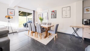 Un espace repas moderne avec une table en bois, des chaises à revêtement gris et un tapis blanc.